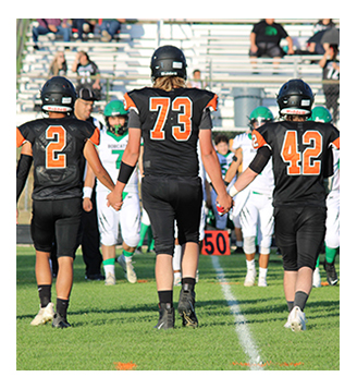 Back view of three football players walking down the field together